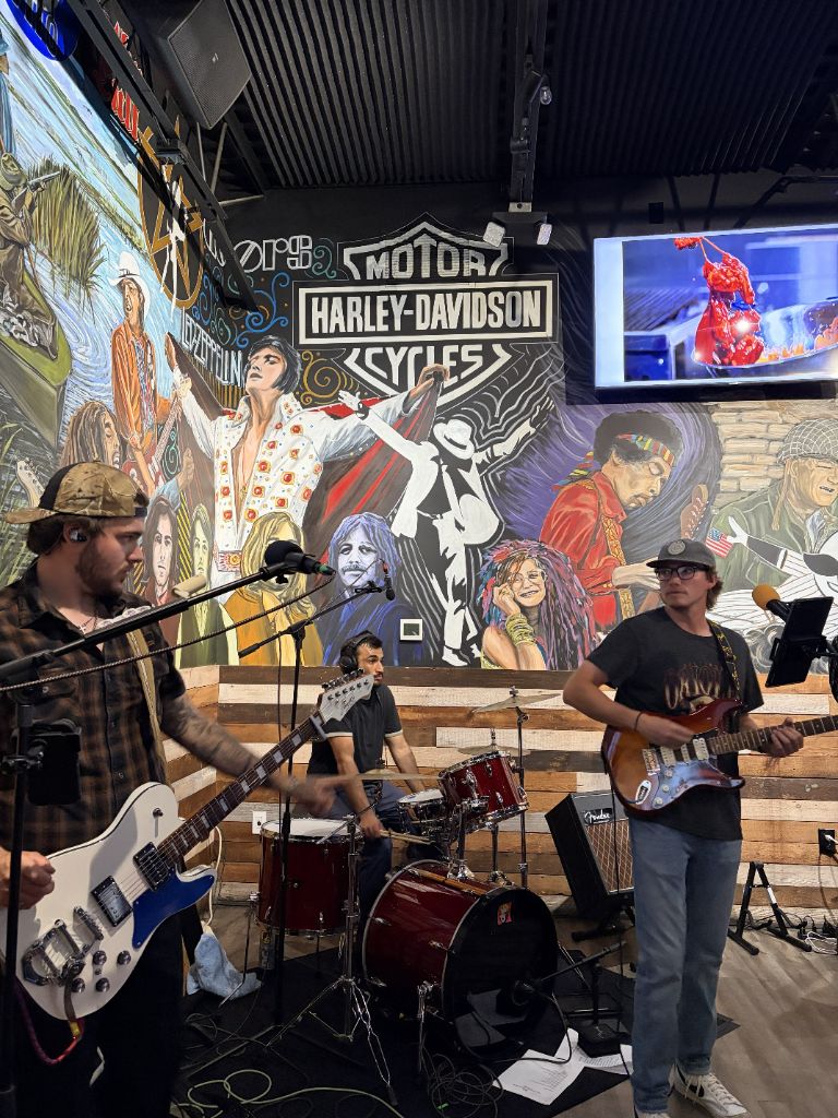 Old Line Revival full band performing in front of Harley Davidson mural